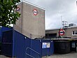 A grey building with a sign on it depicting a blue rectangle superimposed on a white circle superimposed on a red circle