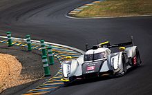 A silver and black Audi sports prototype car being driven in motor racing circuit turn