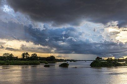 Blue and orange clouds over the Mekong with a pirogue running in the water at sunset in Don Det Laos