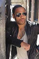 Una fotografía de color de Lenny Kravitz, con gafas de sol y una chaqueta negra.