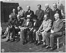 Black and white photograph of two rows of men. Six men each are seated and standing in varying attire