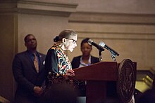 Ginsburg speaking at a podium