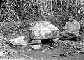 Een Europese man zit naast een heilige steen in de vorm van een huisje en rookt een sigaret, 1934-1938