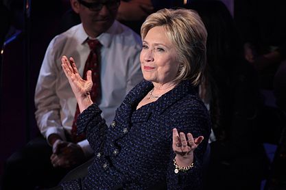 Clinton berbicara di belakang podium dengan mikrofon di tangannya. Dia berbicara pada Brown & Black Presidential Forum di Des Moines, Iowa, pada tanggal 11 Januari 2016.