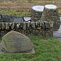 Memorials to the miners who died in the Knockshinnoch mining disaster New Cumnock in 1950. The stone in the foreground tells of the sponsors of the memorials. The nearer conical memorial indicates where the events took place. The text on the third memorial says "To remember Knockshinnoch 1950. The peat valley ahead broke through into the pit killing 13 miners & trapping 116. Wearing oxygen masks the trapped miners were rescued on the 3rd day."