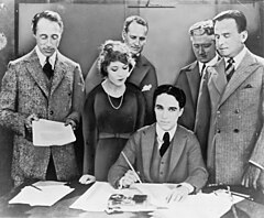 Zleva doprava David Wark Griffith, Mary Pickfordová, Charlie Chaplin (sedící) a Douglas Fairbanks podepisují roku 1919 smlouvu o založení filmové společnosti United Artists. Vzadu stojí právníci Albert Banzhaf (vlevo) a Dennis F. O'Brien (vpravo)