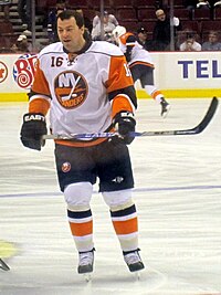 Jon Sim skating on the ice, holding his hockey stick.