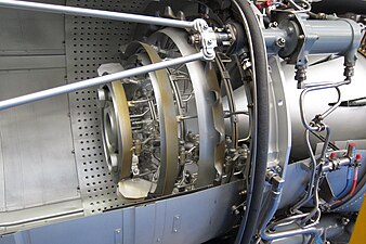 Rolls-Royce Turbomeca Adour turbofan afterburner showing 4 concentric bluff-body flameholders, fuel supply tubes, 2 catalytic igniters, all of which are obstructions to the gas flow which cause a loss of total pressure due to friction from the added turbulence and flow separation. Also shown outside the afterburner are 2 of 8 nozzle operating links from 1 of 4 nozzle operating rams.