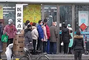 La gente fa la fila fuori una farmacia di Wuhan per comprare mascherine e forniture mediche