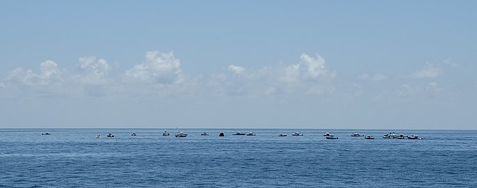 Large numbers of private boats creating a circle around the Endeavour capsule.