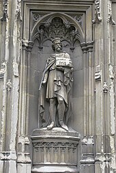 Stone statue of a crowned man holding a sceptre.