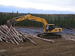 Tracked excavator placing corduroy on muskeg near Rocky Mountain House, Alberta