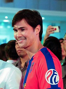 A three-quarter view of Phil Younghusband, wearing a red shirt with a blue stripe, as he his smiling.