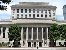 multi-storey light-colored stone building, its front decorated with columns over the main entrance