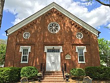 A red brick church building featuring white double doors