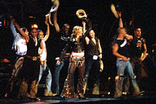 Madonna and her dancers dressed in cowboy garments performing onstage
