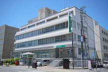 The outside of a building with Japan Post Bank signage in an urban area.