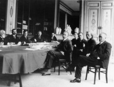 photo en intérieur d'un groupe d'hommes en costume assis autour d'une table.