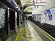 The interior of a building with a rounded ceiling and walls and a white sign hanging from the ceiling reading "Way out Central line"