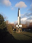 Réplique du premier prototype de V2 tiré avec succès en octobre 1942 photographiée en 2002 au musée de Peenemünde. Comme l'original, sur l'empennage du missile se trouve un dessin rendant « hommage de façon humoristique au film »[29] La Femme sur la Lune de Fritz Lang (1929). La peinture en damier noir et blanc permettait « d'analyser les mouvements de la fusée lors du dépouillement des films réalisé pendant le vol »