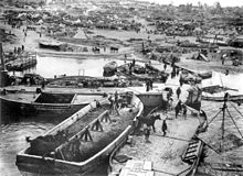 Vyloďování dohodových sil na poloostrově Gallipoli. V popředí čluny z nichž jsou na břeh vyváděni koně. V pozadí tábor hemžící se vojáky.
