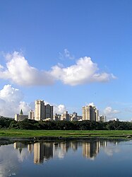 A number of multistory residential and commercial buildings overlooking a water body, taken against the backdrop of a clear blue sky with a few cirrus clouds