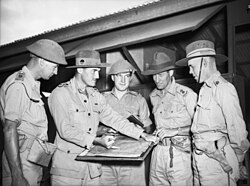 A group of military officers in conference around a map