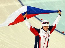 Photographie d'une femme brandissant le drapeau tchèque au-dessus de sa tête.