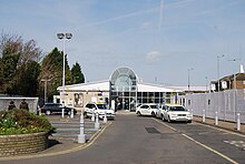 View of Rainham Railway Station and forecourt from the front, there is a side-gate for access in the railings along the right hand side