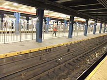 View of the center IND platform, between the two express tracks. There are fences on either side of the platform.