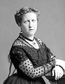 Head and shoulders photograph of a middle-aged Isabel wearing a flower hat