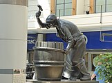 Statue of a cooper hammering a shaping truss onto the staves of a barrel