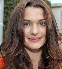 Photographie du visage de Rachel Weisz en 2012. Elle a la peau claire, les cheveux châtain mi-longs et les yeux noisette. Elle sourit à l'objectif.