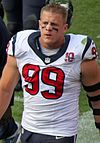 A Caucasian football player without his helmet on, walking down the sideline. Eyeblack is visible