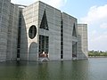 Image 46Jatiyo Sangsad Bhaban is the National Assembly Building of Bangladesh, located in the capital Dhaka. It was created by architect Louis I. Kahn and is one of the largest legislative complexes in the world. It houses all parliamentary activities of Bangladesh. This photo offers a close view of a section of the parliament building. Photo Credit: justinstravels