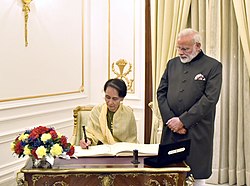 The State Counsellor of Myanmar, Aung San Suu Kyi signing the visitors’ book, at Hyderabad House, in New Delhi on January 24, 2018. The Prime Minister, Shri Narendra Modi is also seen