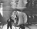 Photographie en noir et blanc d'un engin spatial plongé dans une piscine pour un entraînement à gravité réduite.