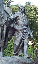 Outdoor statue of man in long cape holding a horse's reins