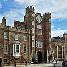 A brown brick palace with a gatehouse and a large clock.