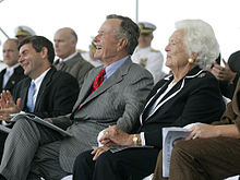 Barbara and George are seated beside one another among an audience