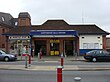 A brown-bricked building with a rectangular, dark blue sign reading "NORTHWOOD HILLS STATION" in white letters all under a blue sky with white clouds