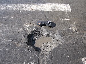 Detail of pothole, showing presence of water in soil structure, on a road in Montréal, Québec