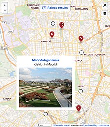 Screenshot of a map in fulsize view. There are several round markers in grey and one classic marker in red. One round marker shows a popup with a title, description and image.