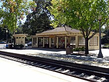 An image of a train station, including tracks, platforms, and a shelter.