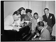 Jack Teagarden, Dixie Bailey, Mary Lou Williams, Tadd Dameron, Hank Jones et Milt Orent autour de Dizzy Gillespie au piano, dans l'appartement de Mary Lou Williams.