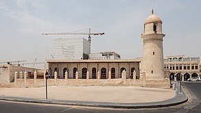 An old mosque minaret stands out in front of an under construction tower of the Musheireb downtown Doha development.