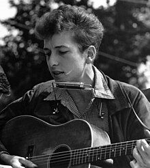 A man playing an acoustic guitar outdoors