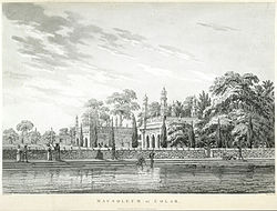 A stone building with onion-domed minarets and a body of water adjoining it. Some men are bathing; others are engaged in conversation. A stone wall separates the water from the building's garden and its leafy trees.