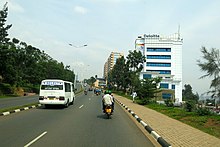 Photograph of a street, including buildings, vehicles and pedestrians