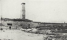 A black-and-white photograph of a low building with a tall chimney. The structure served as a crematorium.